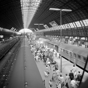 881966 Gezicht op de perrons onder de eerste perronkap van het N.S.-station Amsterdam C.S. te Amsterdam.